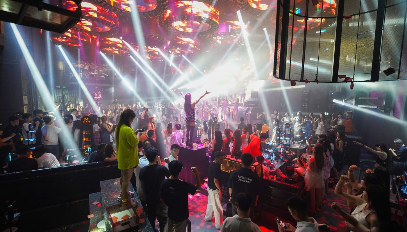 A busy nightclub floor lit by bright beams as the crowd dances