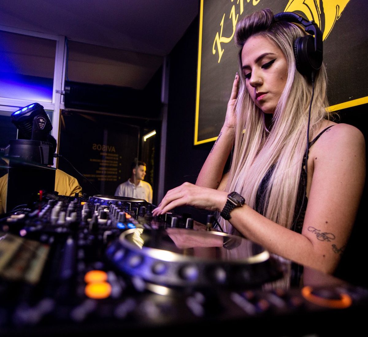 A DJ mixing with headphones on in a live club booth