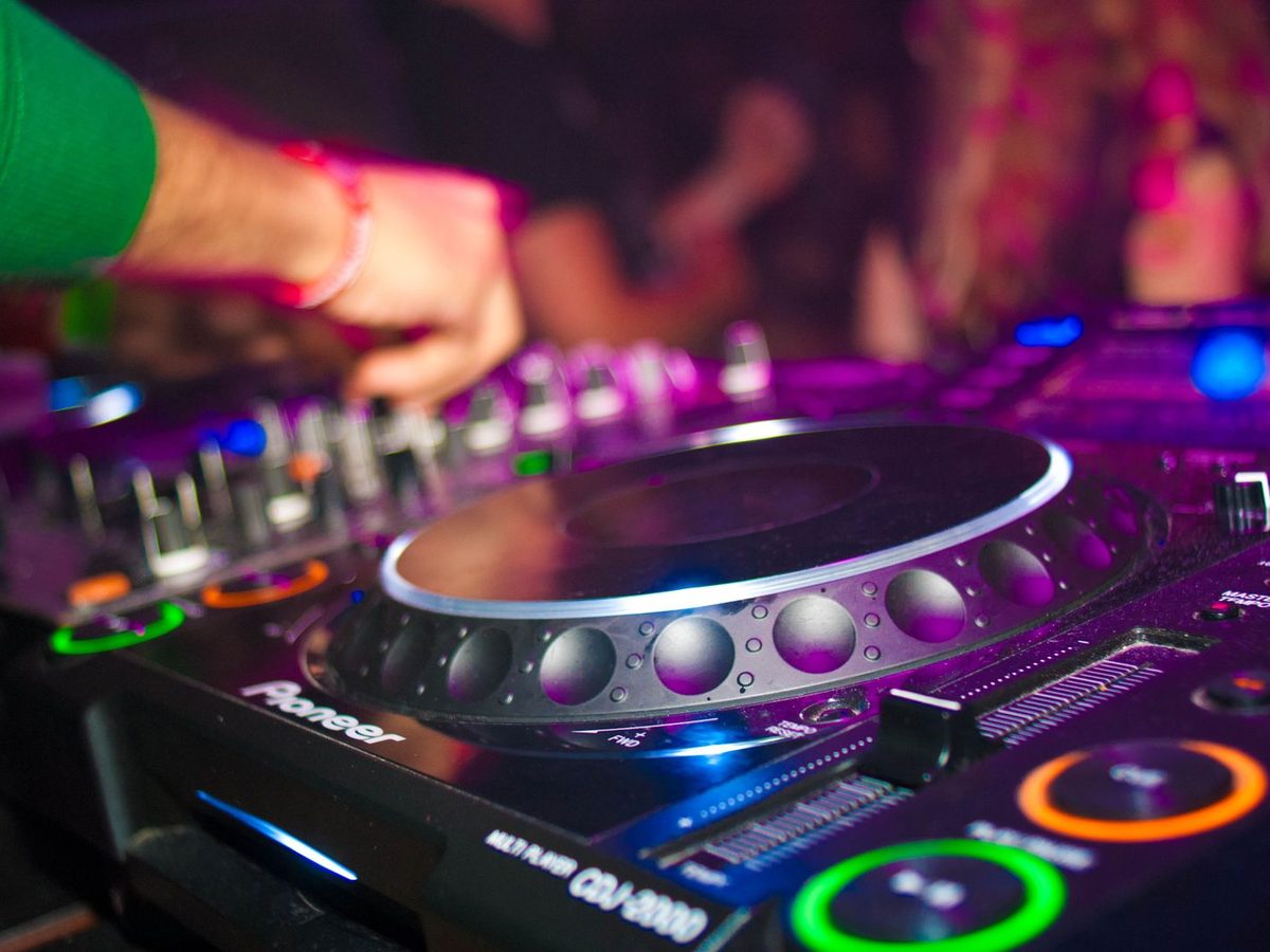 Close-up of a Pioneer CDJ jog wheel glowing under coloured club lights