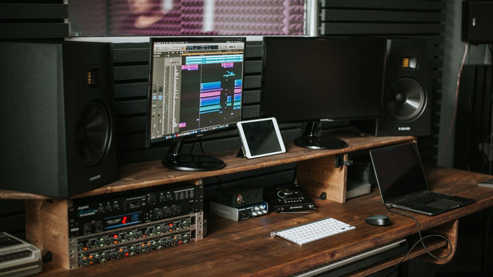 Studio monitor speakers set up on a producer's desk in a warm-lit studio